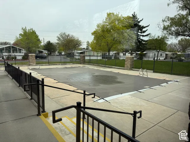 Outdoor swimming pool area featuring a dark pool cover and concrete surround