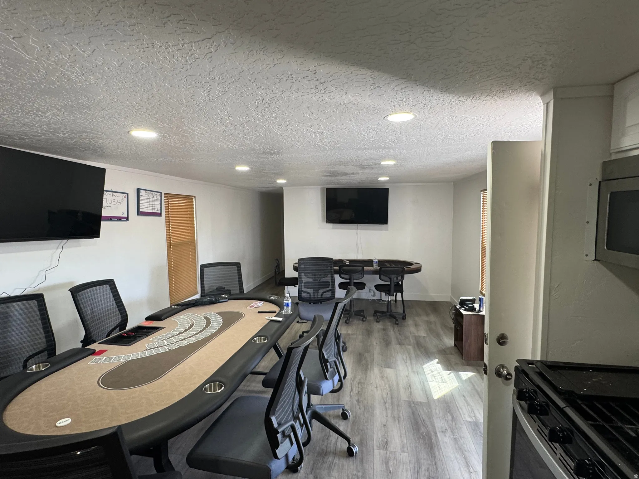 Spacious interior room featuring wood-finish flooring, white walls, and recessed lighting