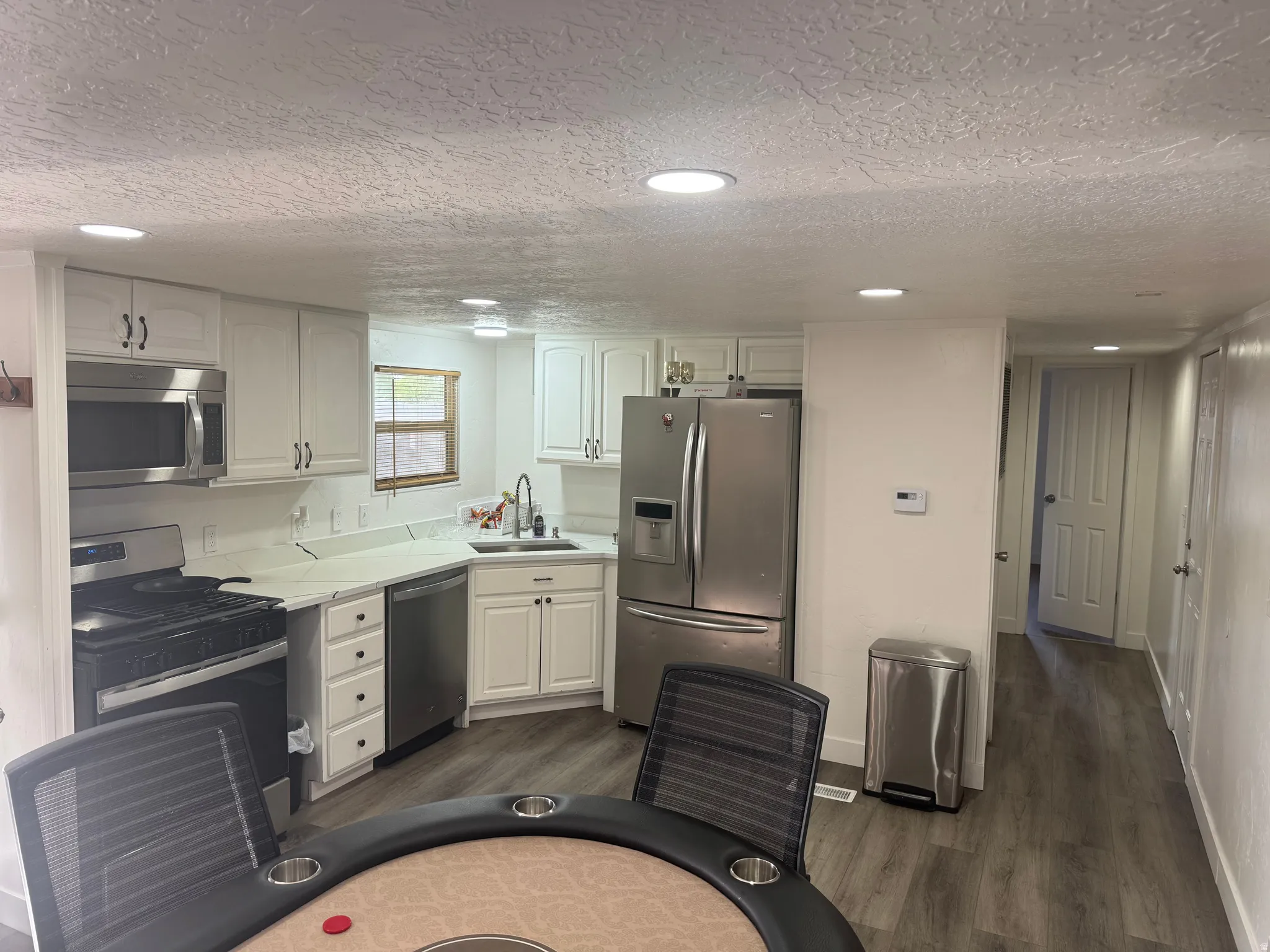 Modern kitchen featuring white cabinetry, stainless steel appliances, light-toned countertops, a tile backsplash, and recessed lighting