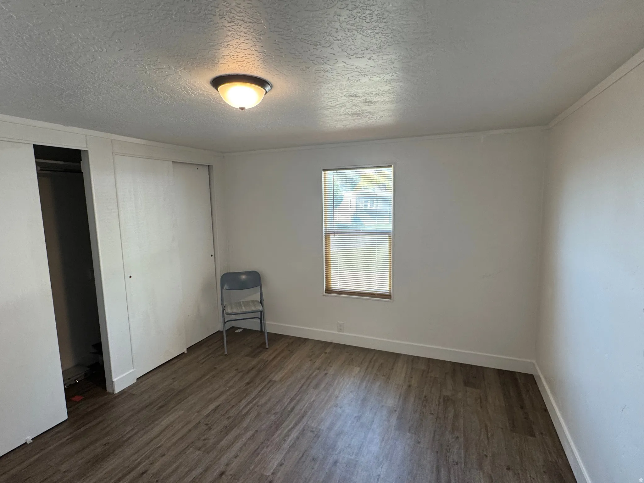 Bright room with wood-finish flooring, a window offering natural light, and a built-in closet with sliding doors