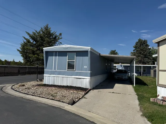 Light blue manufactured home with white trim and a covered carport