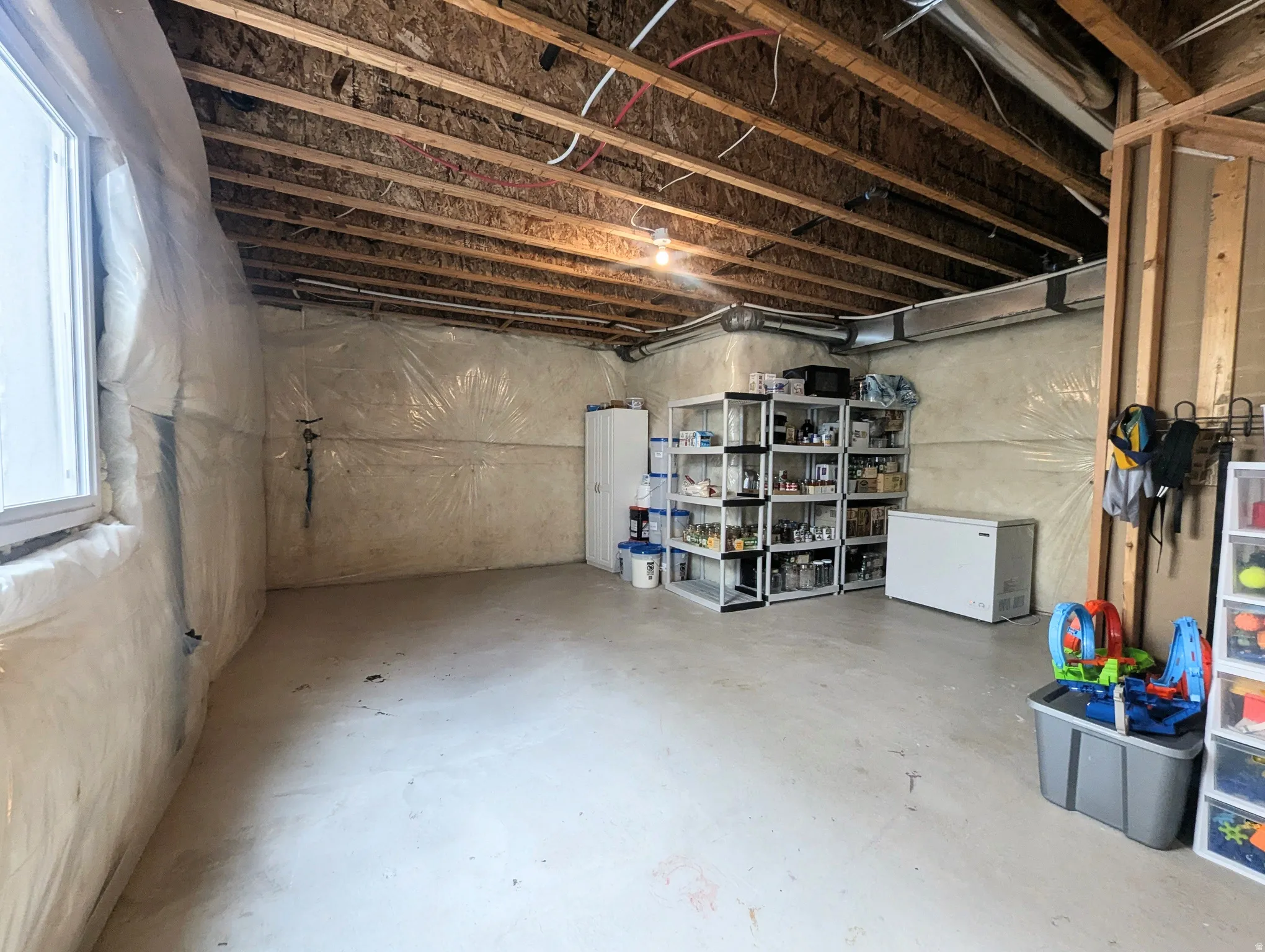 Unfinished basement with exposed ceiling joists and concrete flooring