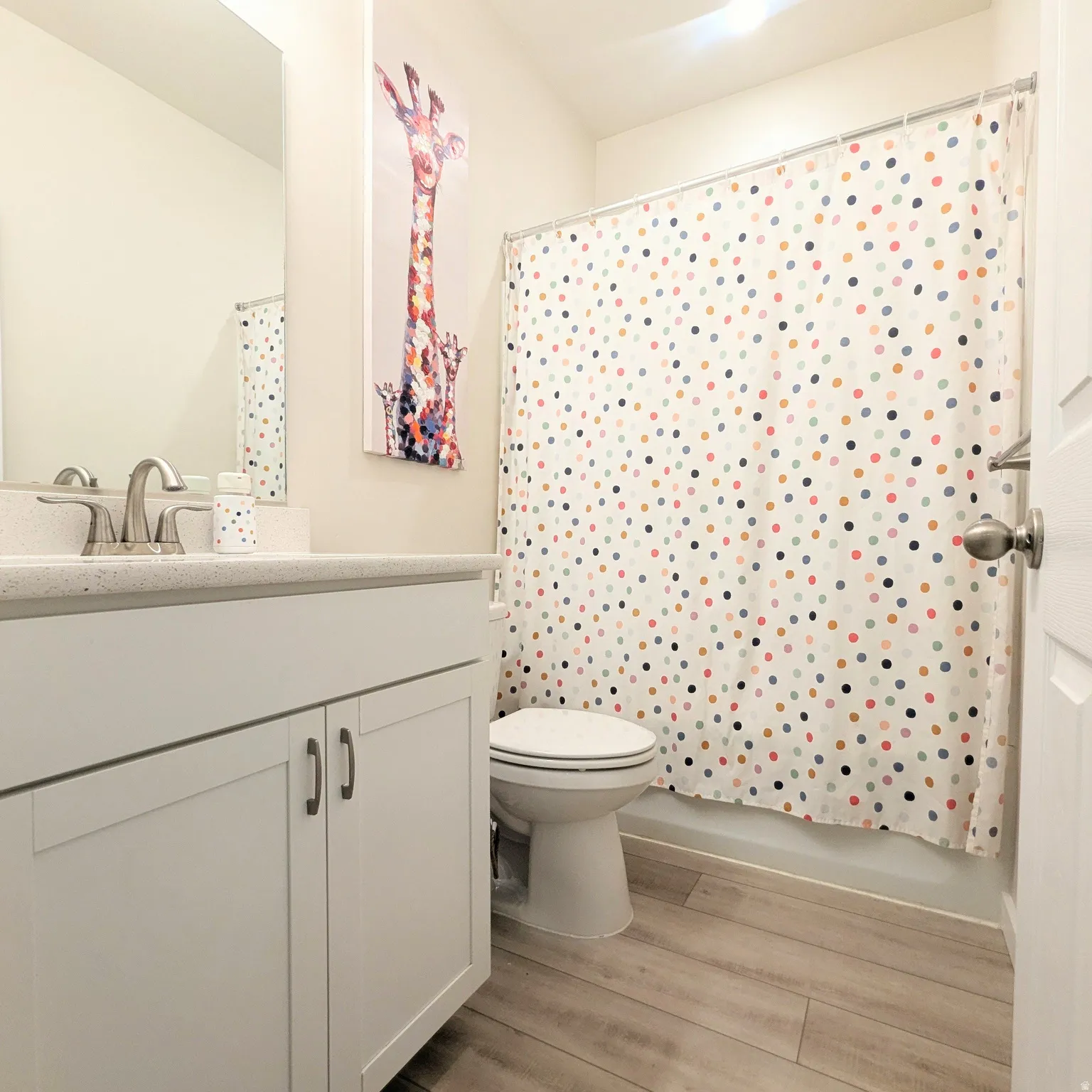 Bathroom featuring a white vanity with shaker-style cabinetry, a solid surface countertop, and a stainless steel faucet