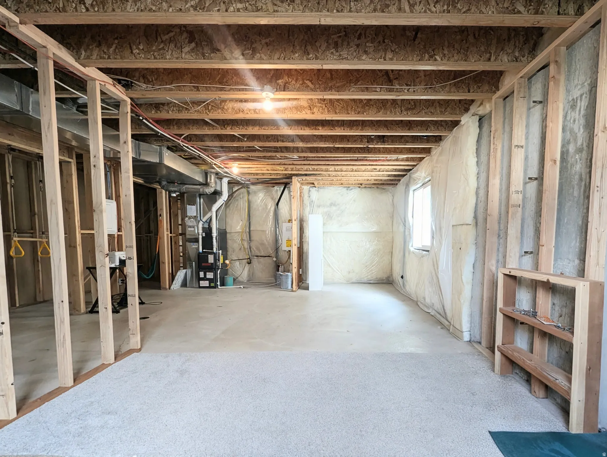 Unfinished basement featuring exposed wood joists, framed wall partitions, and an exposed HVAC system