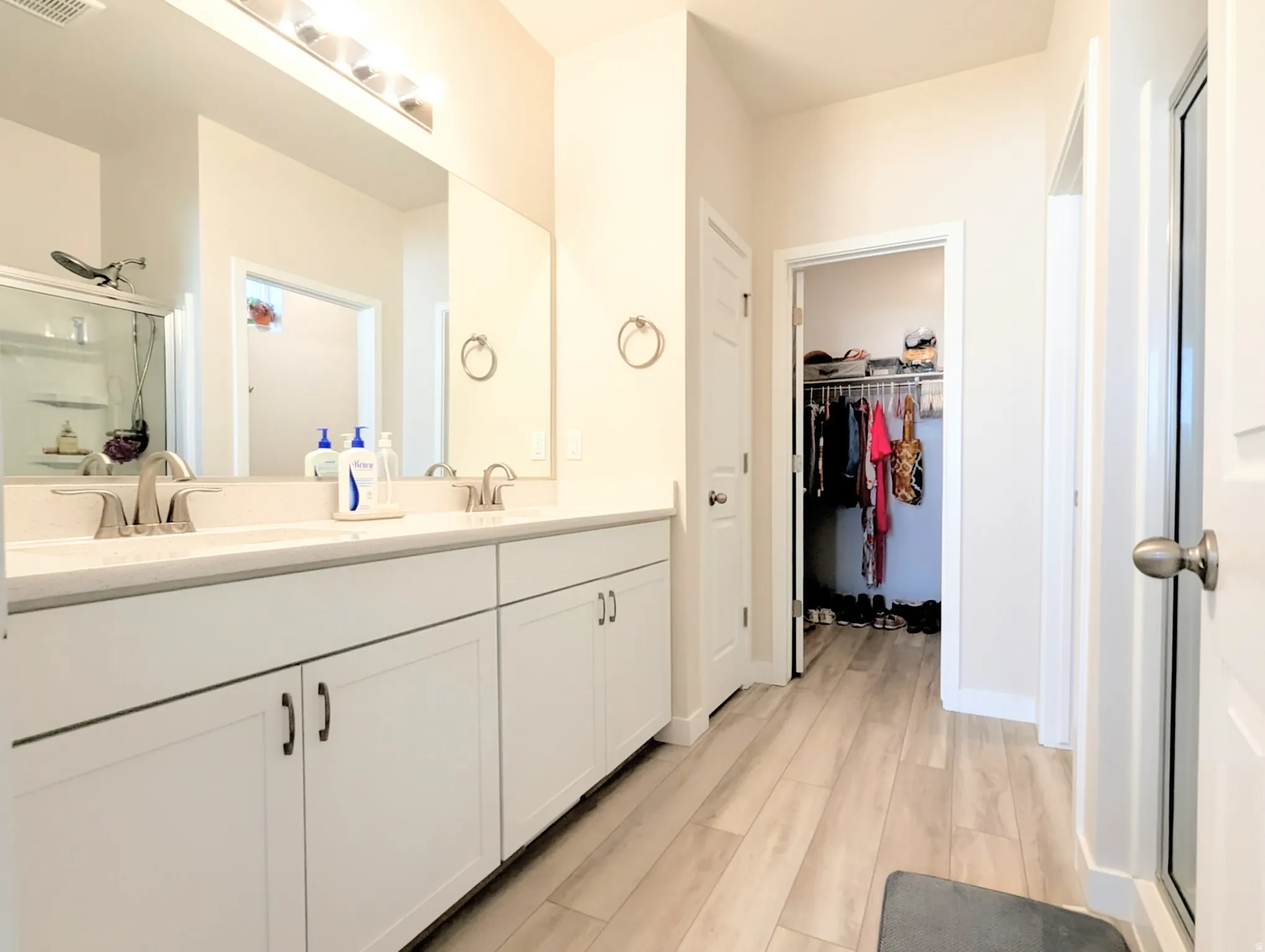 Bathroom featuring a double vanity with white cabinetry, dual undermount sinks, and a single large mirror