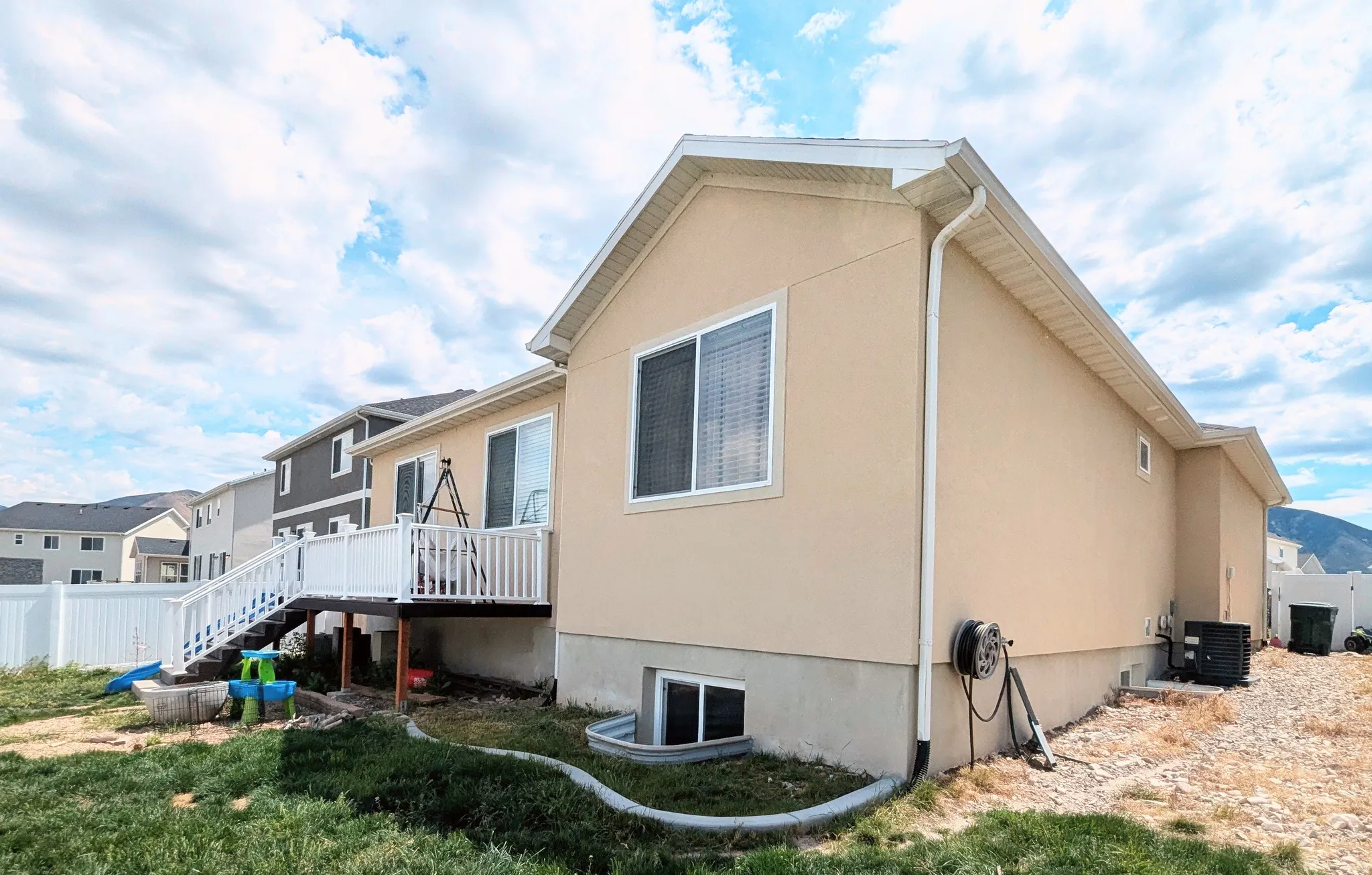 Rear exterior featuring a spacious deck with white railings, stairs to the yard, and a sliding glass door