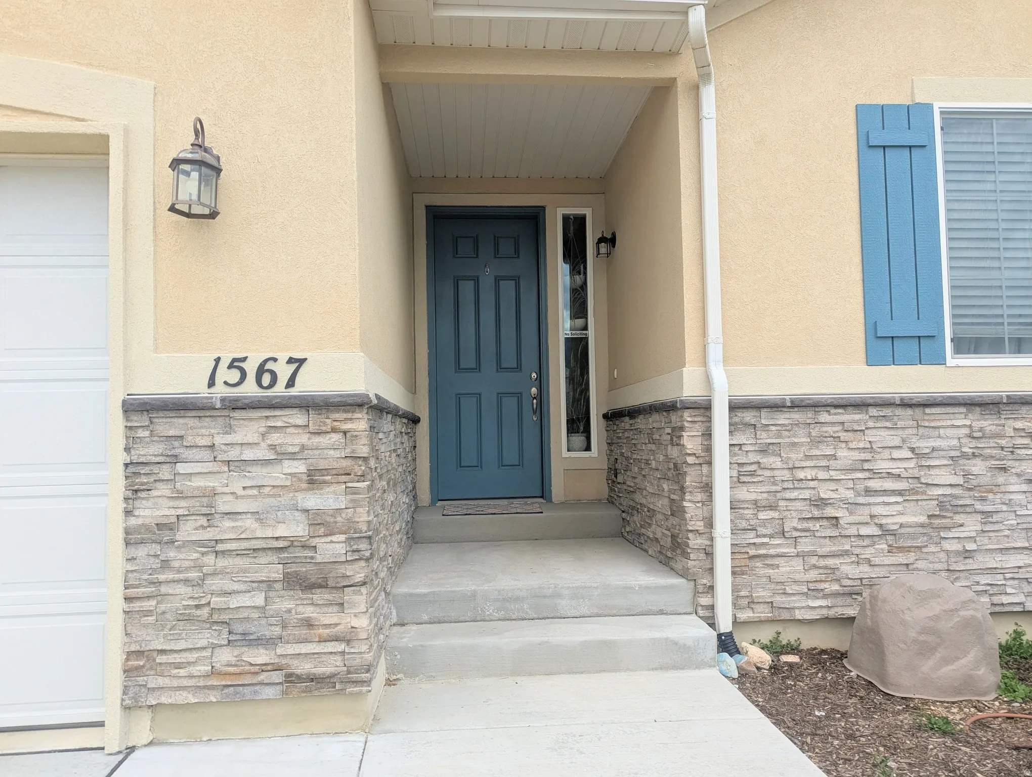 Welcoming entryway featuring a prominent teal front door, complementing sidelight windows, and decorative blue shutters
