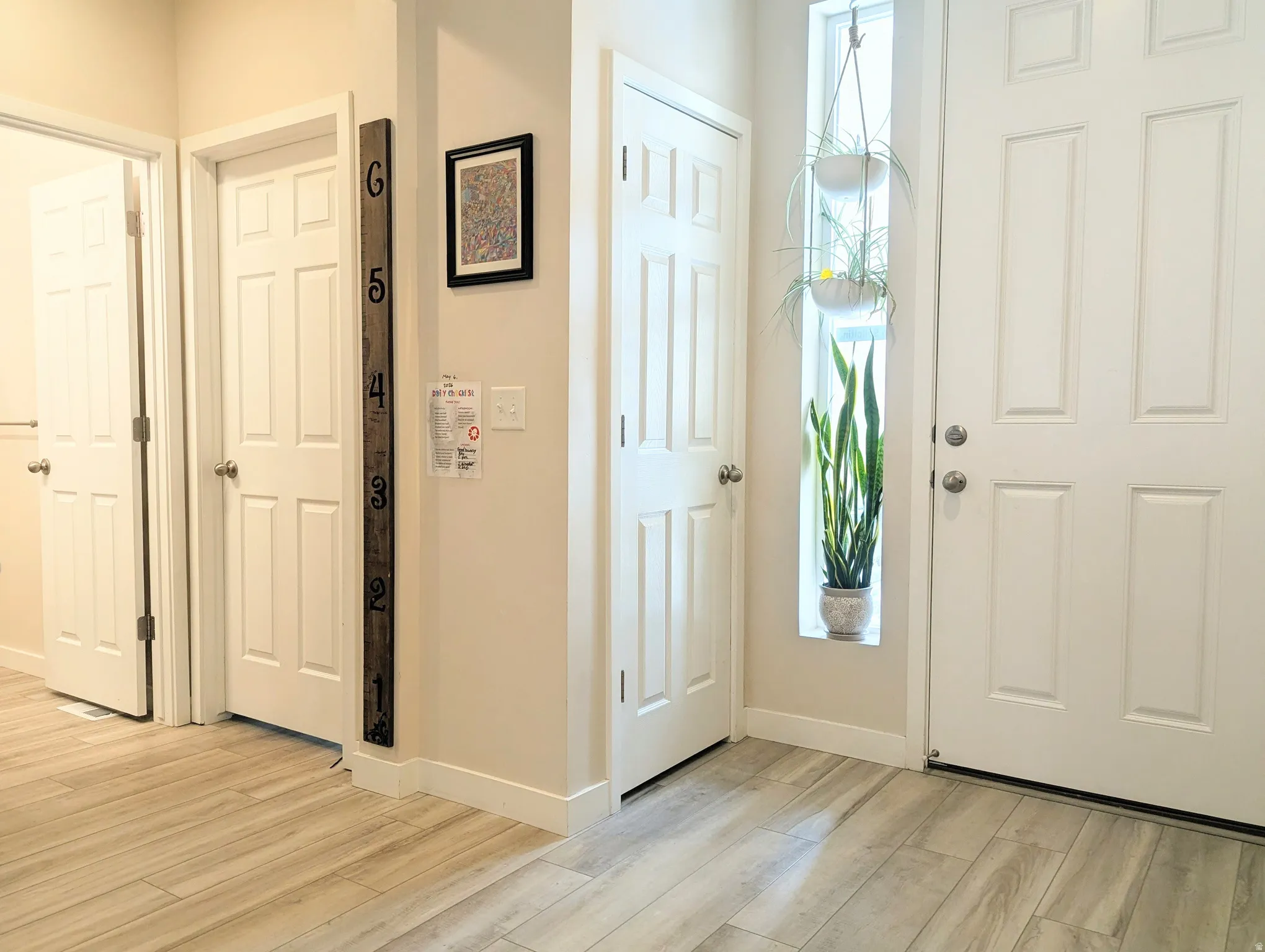 Entryway featuring wood-finish flooring, a white paneled door, and a vertical window accent