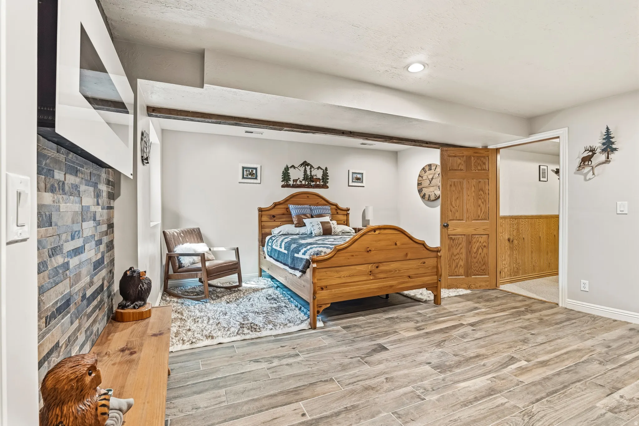 Spacious room featuring wood-finish flooring, a recessed lighting fixture, and a decorative fireplace with a stacked stone facade