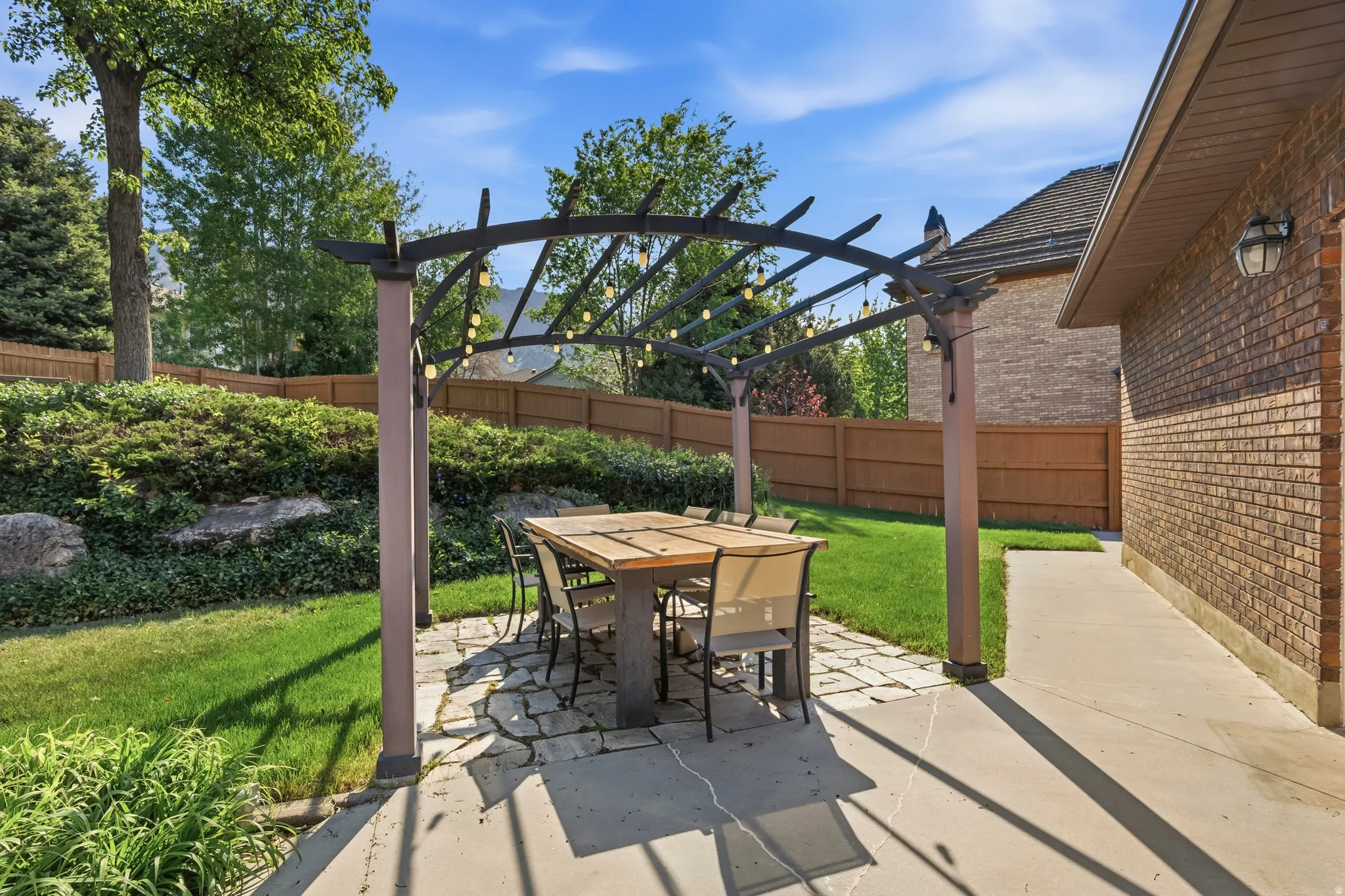 Outdoor living space featuring a pergola with string lights, a flagstone patio, and a dining table