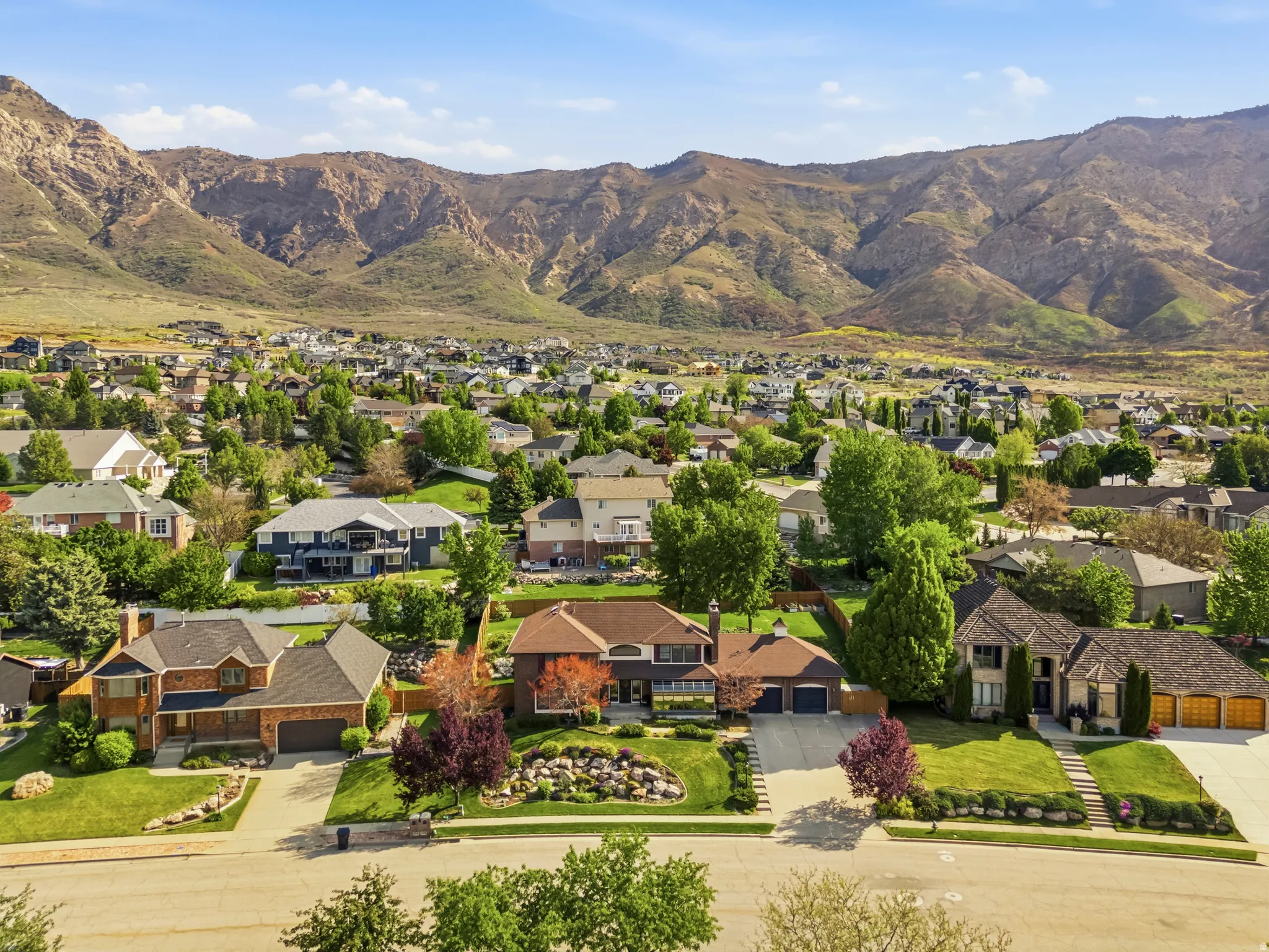 Residential neighborhood featuring varied home styles, mature landscaping, and mountain backdrops