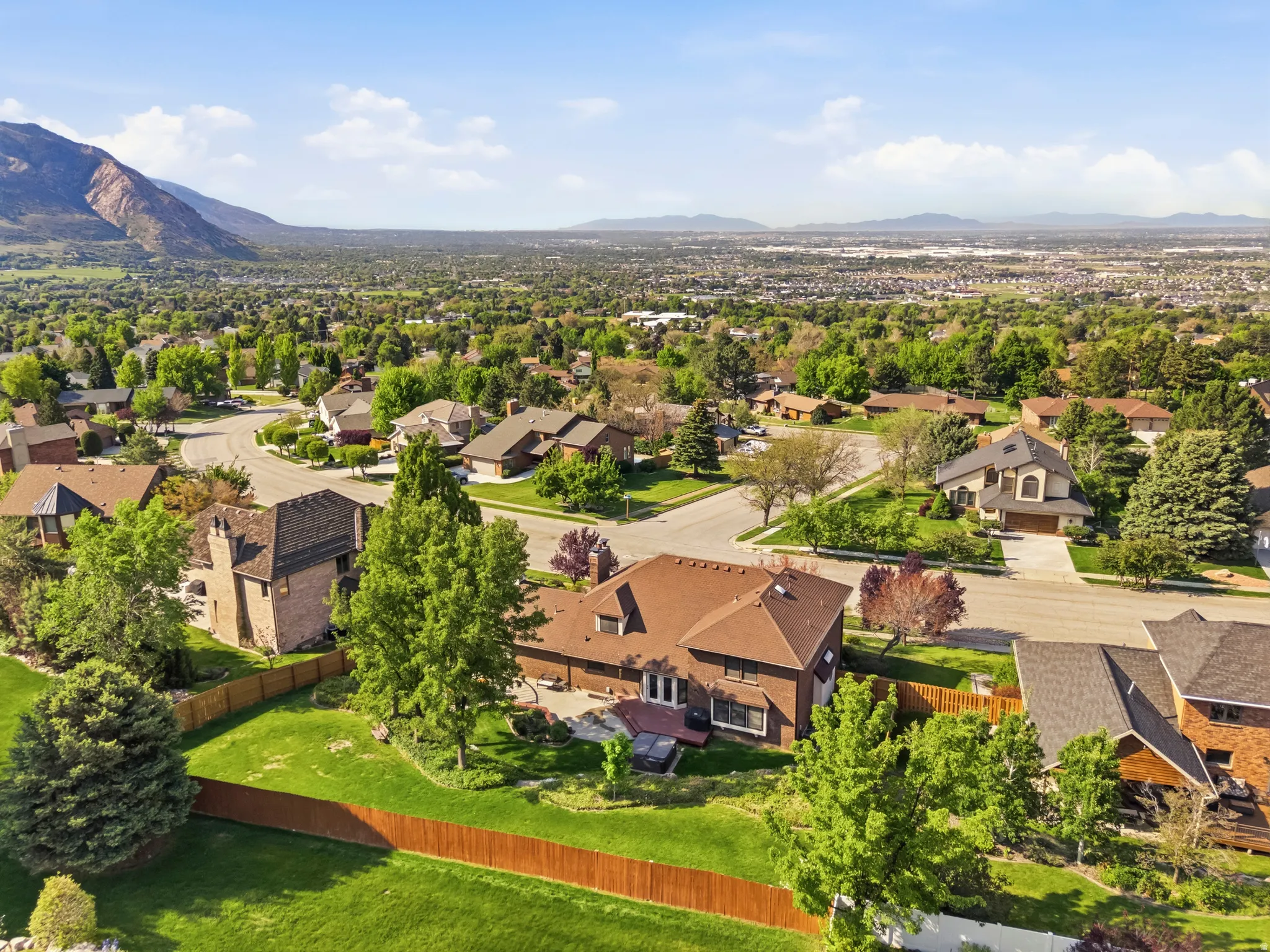Expansive residential area featuring numerous single-family homes with mature trees and visible mountain ranges in the distance