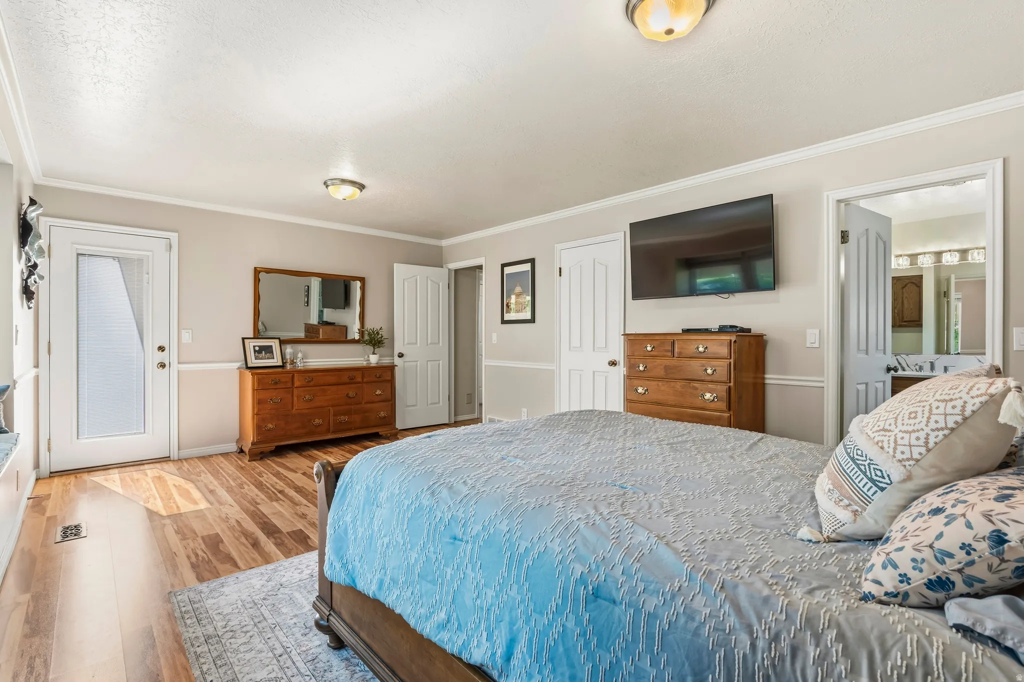 Bedroom featuring wood-finish flooring, neutral wall tones, crown molding, and a built-in window bench