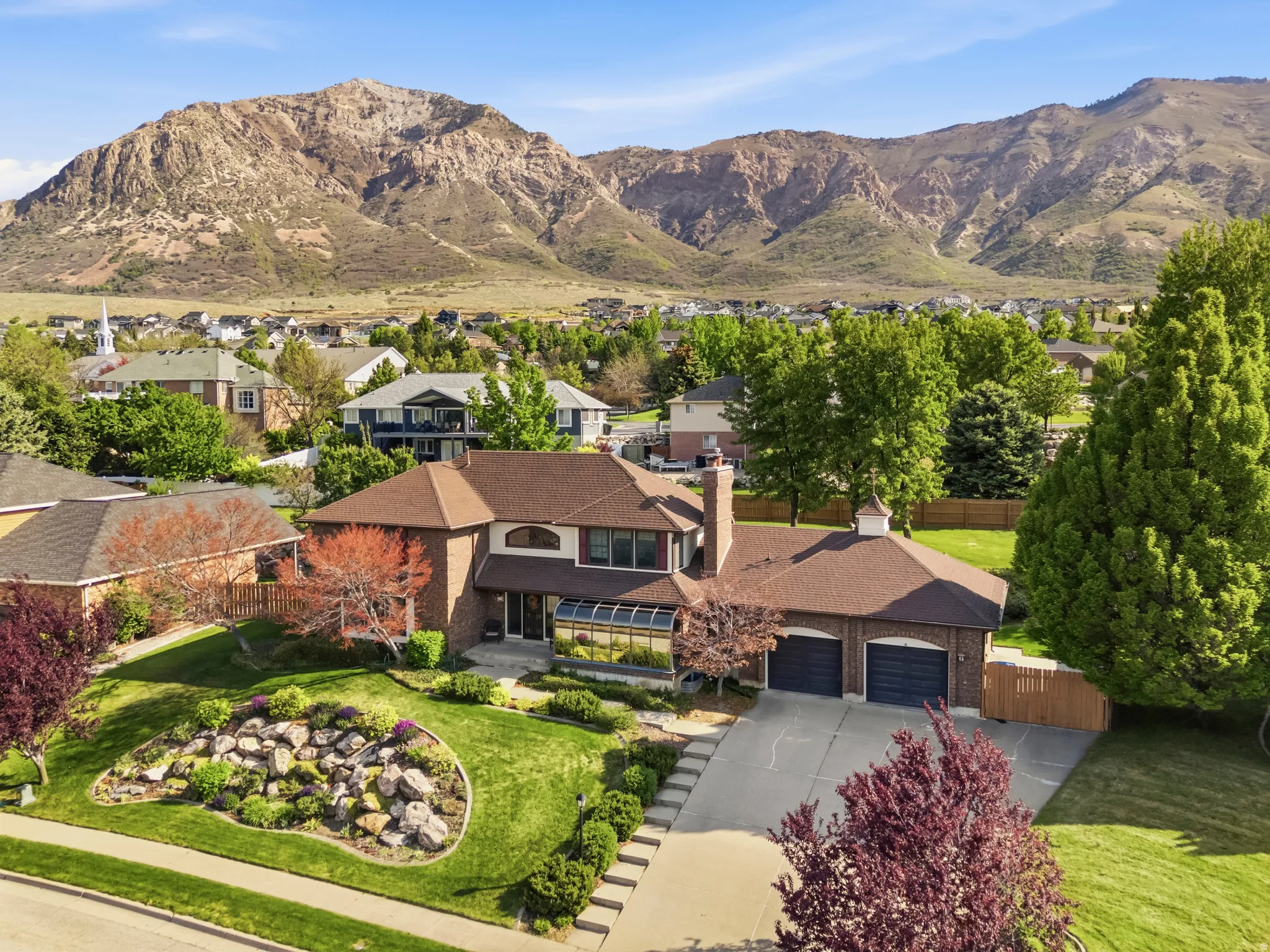 Brick two-story residence featuring a brown shingle roof and a prominent two-car garage