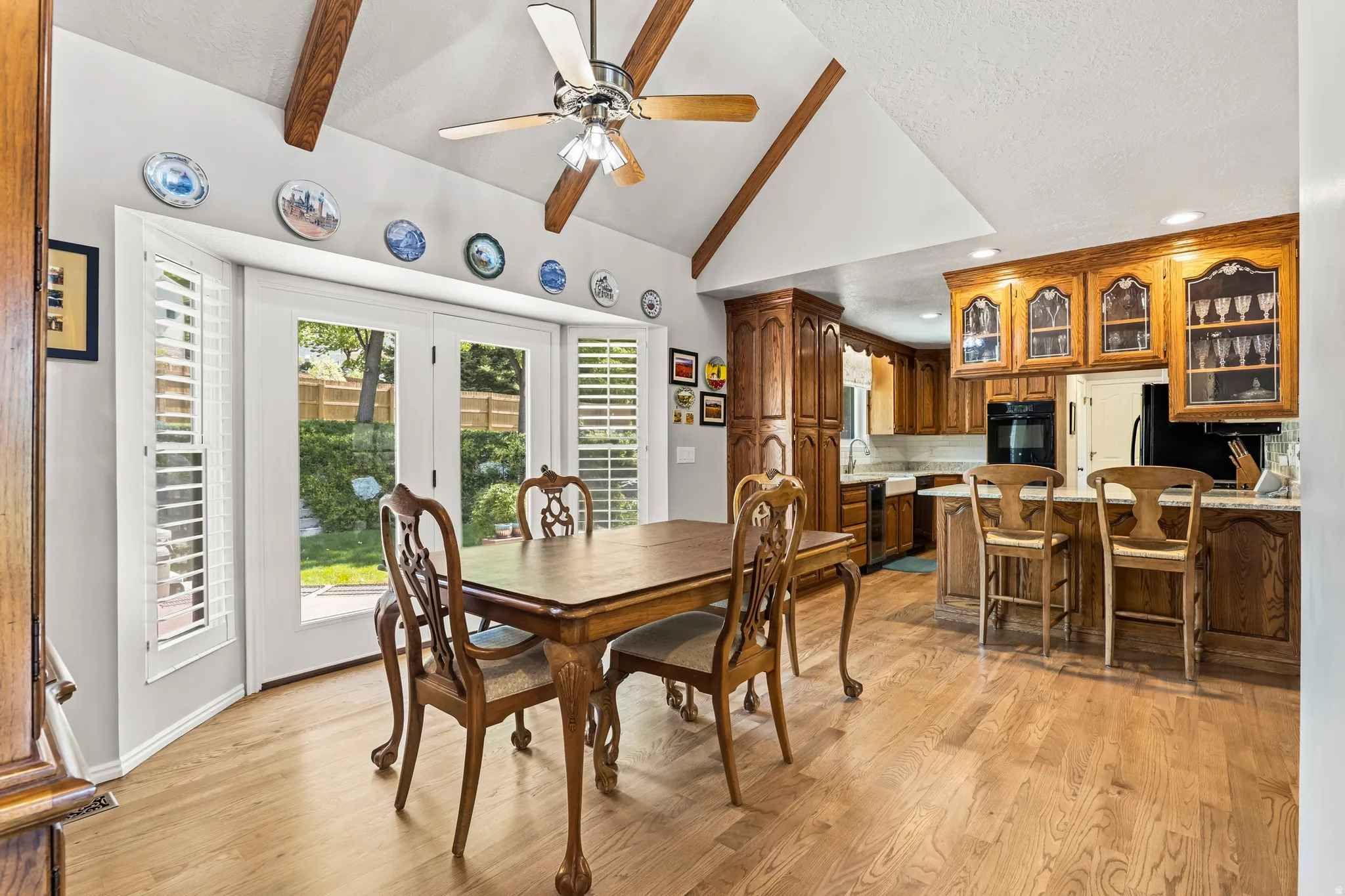 Open-concept dining area with vaulted ceilings featuring exposed wood beams and a ceiling fan