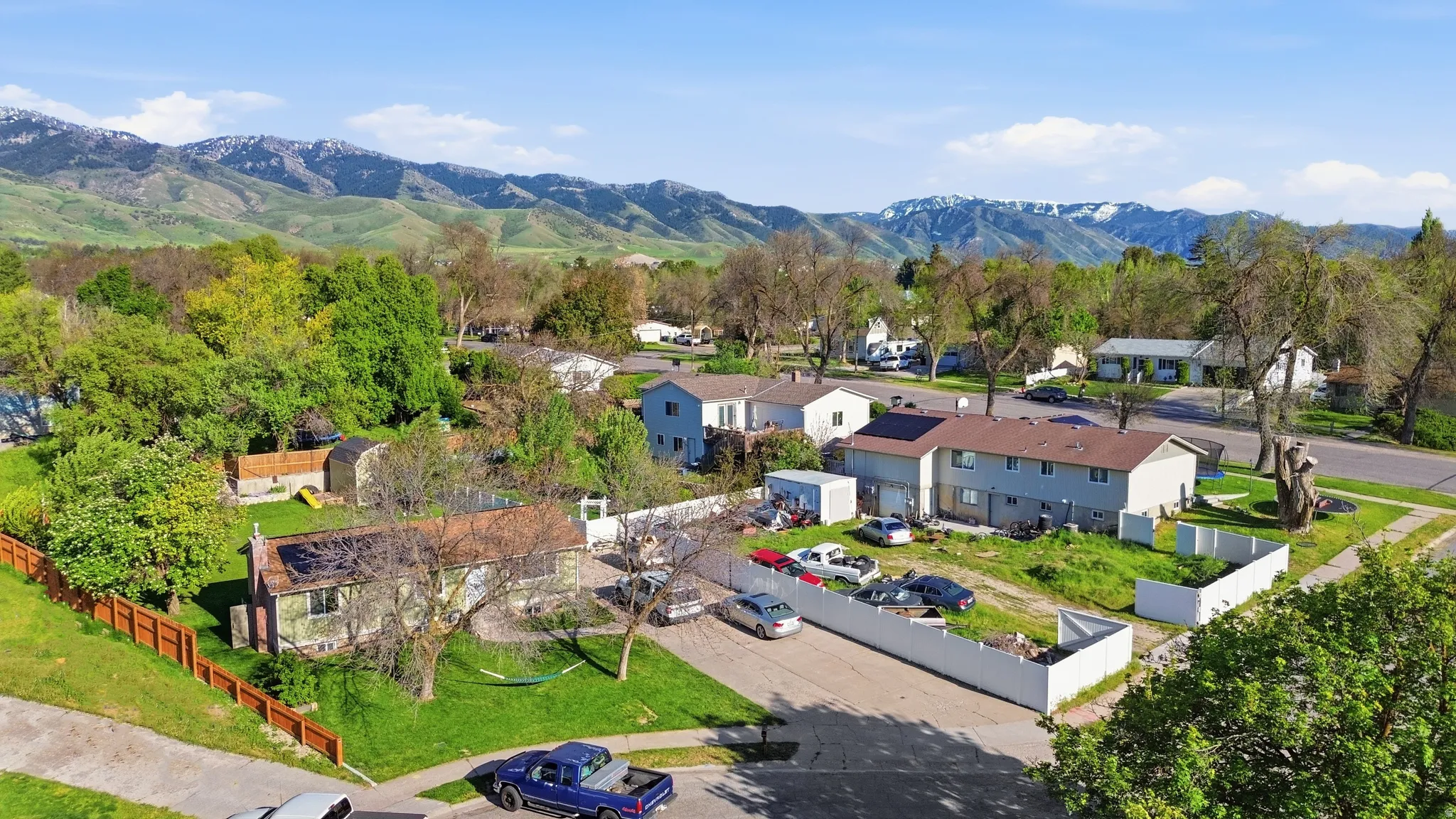 Expansive property featuring multiple structures, mature trees, and a mountain backdrop