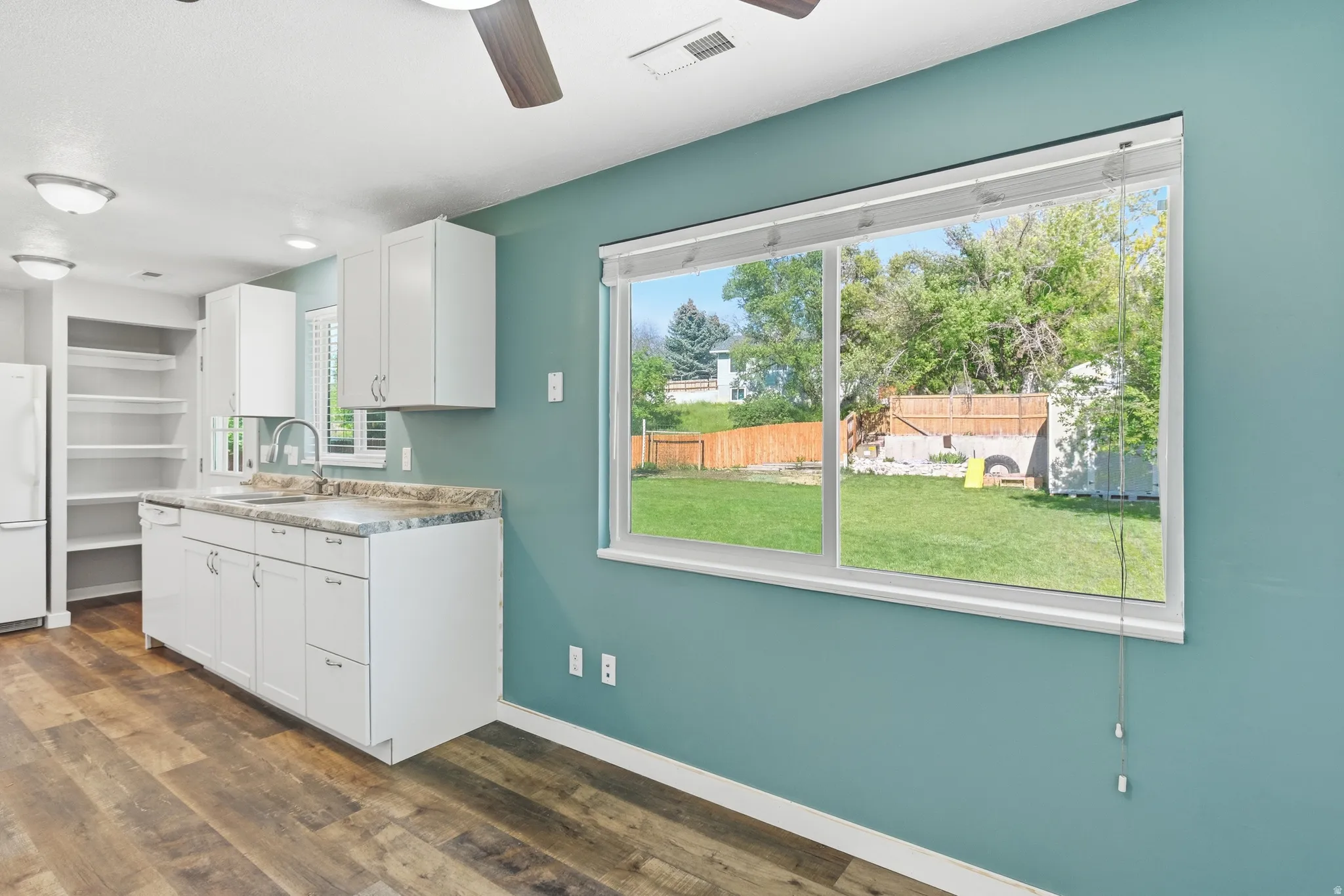 Contemporary kitchen featuring white cabinetry, a stainless steel sink, and wood-finish flooring