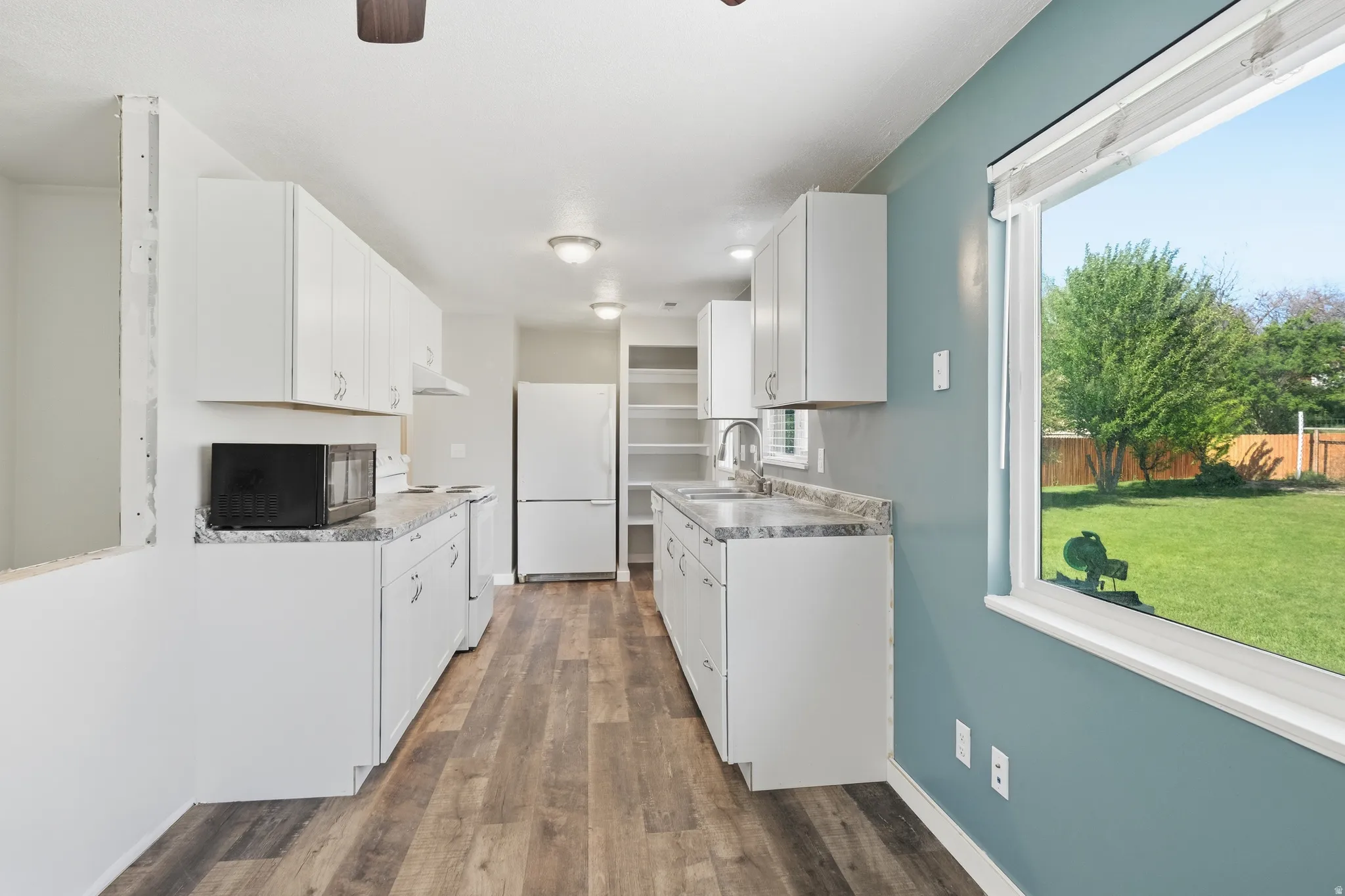 Kitchen featuring white cabinetry, gray patterned countertops, and wood-finish flooring