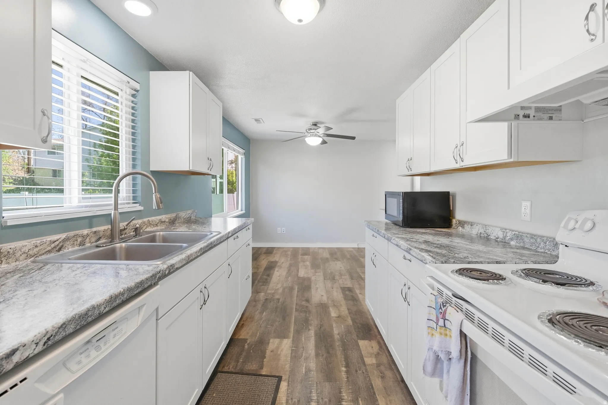 Galley kitchen featuring white cabinetry, light-toned countertops, wood-finish flooring, and recessed lighting