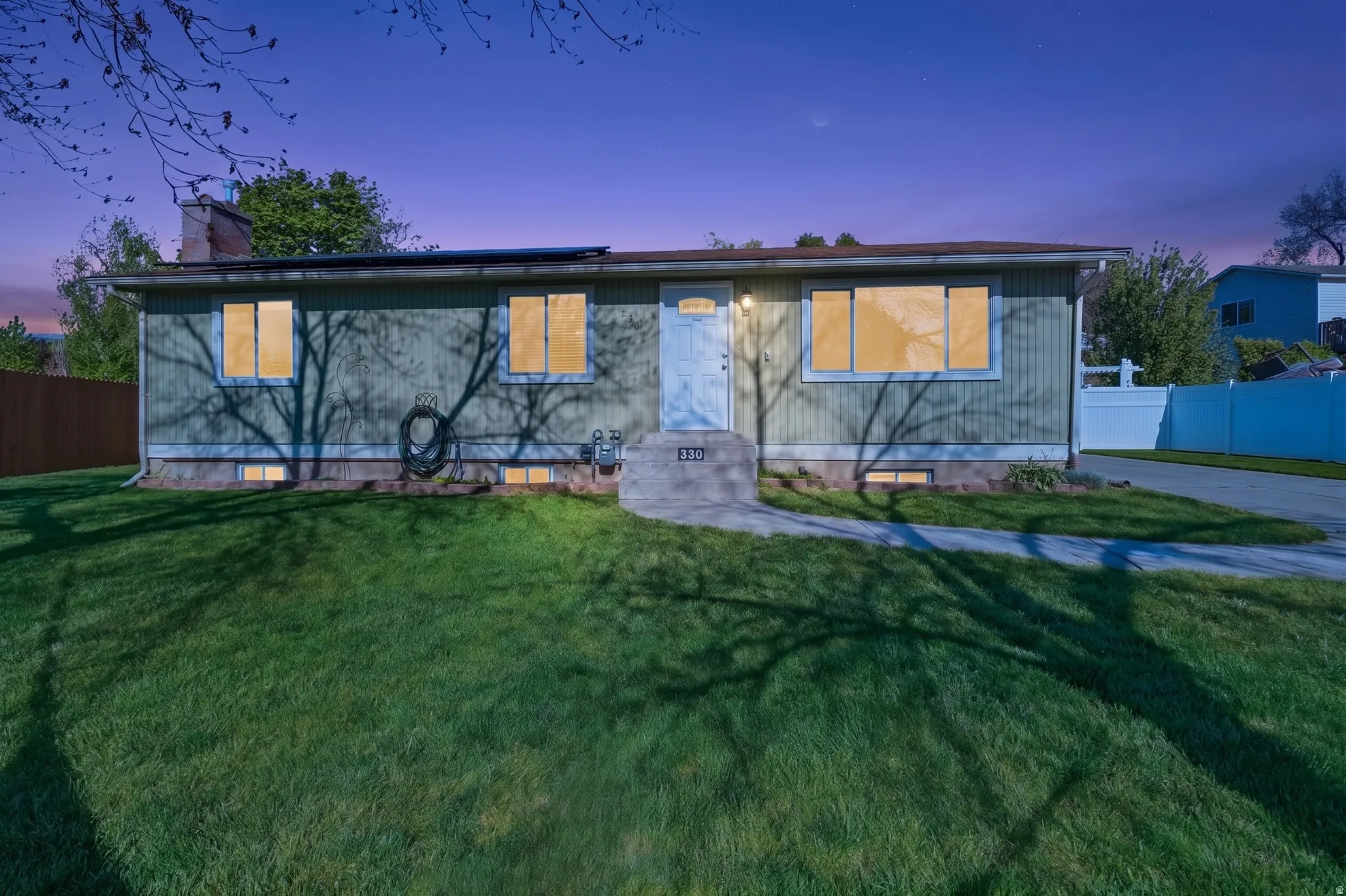 Ranch-style exterior with vertical siding, an attached concrete driveway, and a front lawn