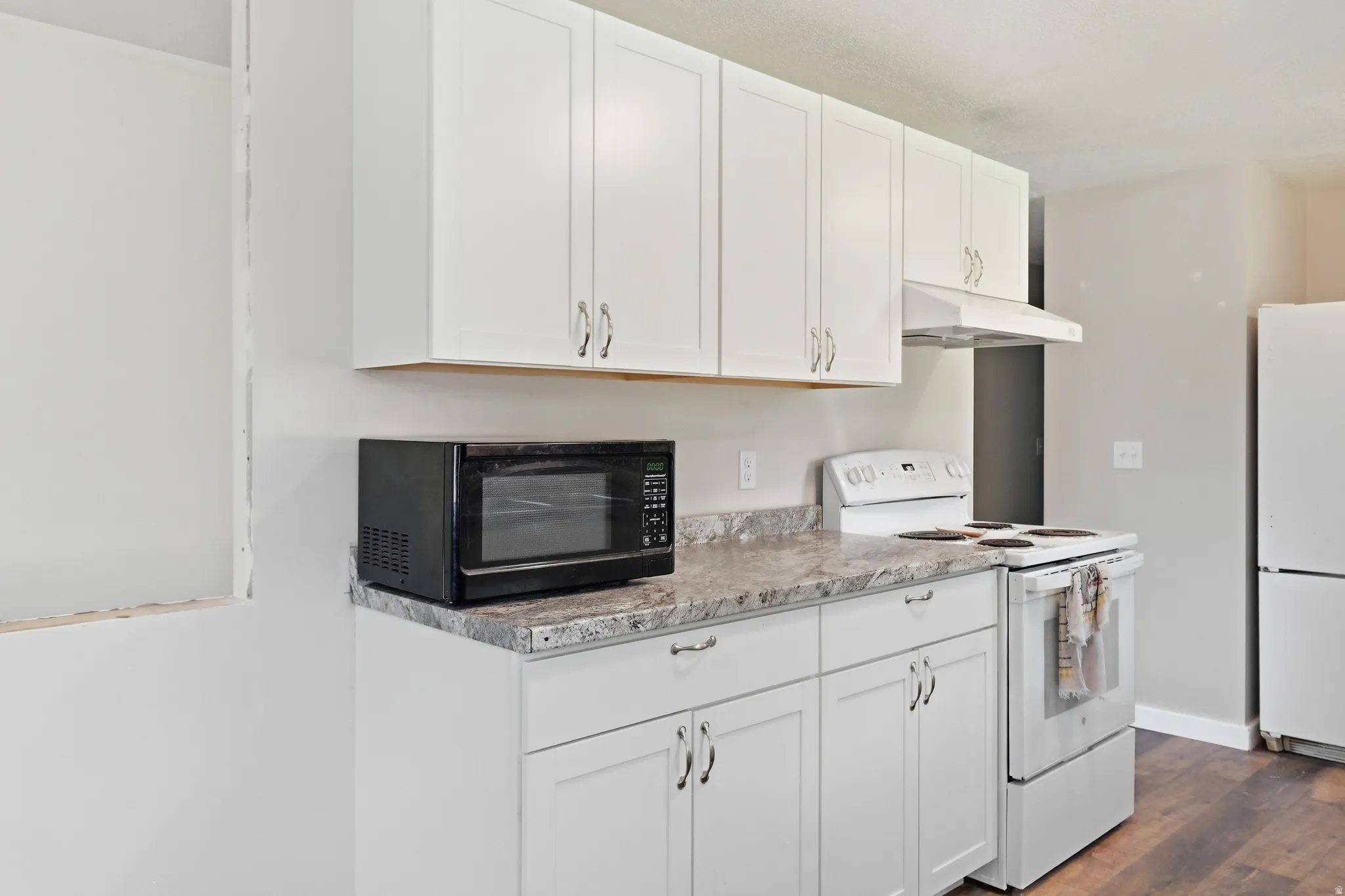 Kitchen featuring white cabinetry, grey countertops, white range with hood, and wood-finish flooring
