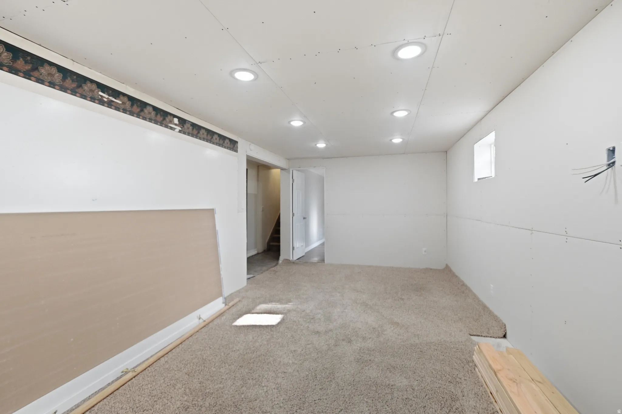Spacious interior featuring recessed lighting, a small window, and a door leading to a staircase