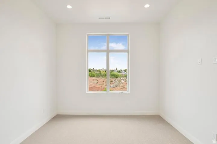 Neutral interior featuring a large multi-pane window, recessed ceiling lighting, light-toned carpet, and clean white walls