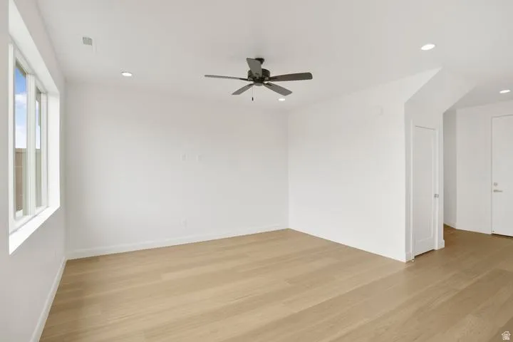 Spacious interior room featuring light wood-finish flooring, crisp white walls, and a multi-pane window
