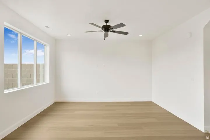 Bright room featuring a large window, a modern ceiling fan, recessed lighting, wood-finish flooring, and crisp white walls