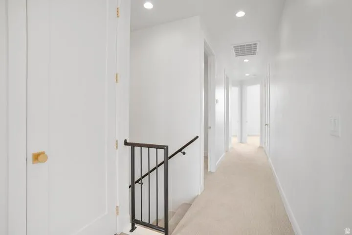Bright hallway with recessed lighting and light-colored carpeting