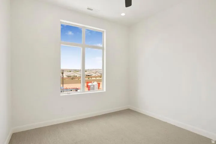 Bright interior space featuring a large multi-pane window, recessed lighting, ceiling fan, and light-toned carpet flooring