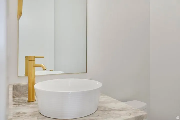 Modern vessel sink with a gold-tone faucet set against a stone-finish countertop