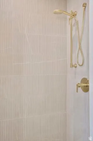 Shower enclosure featuring vertical ribbed tile and gold-tone fixtures