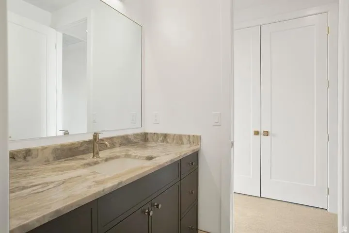 Bathroom vanity featuring a light-toned stone countertop with an integrated rectangular sink