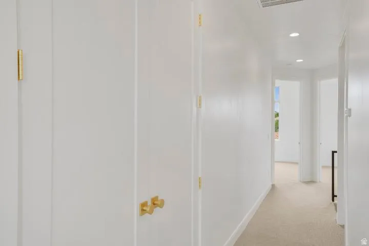 Hallway featuring neutral carpet flooring, recessed ceiling lighting, and white walls