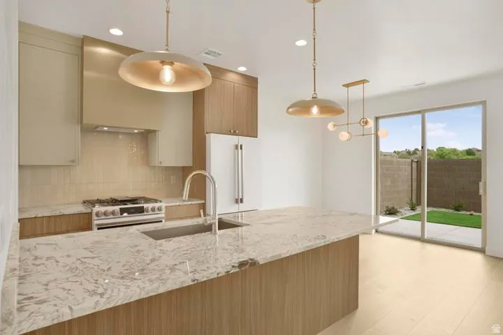 Contemporary kitchen featuring a large island with an undermount sink, stainless steel appliances, a gas range, and wood-finish flooring
