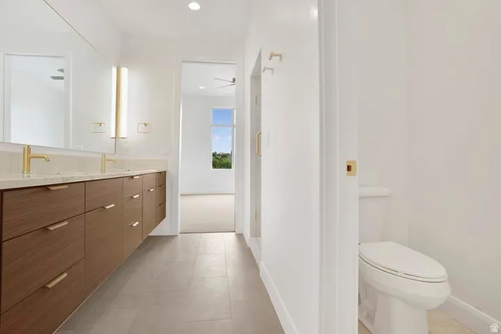 Double vanity featuring wood-finish cabinetry, light-toned countertop, and gold-finish fixtures