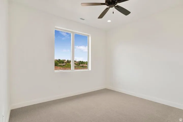 Room featuring a window with a distant landscape, neutral carpeting, a ceiling fan, and recessed lighting