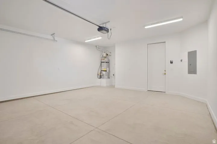 Spacious garage with concrete flooring, automatic garage door opener, and integrated utility access