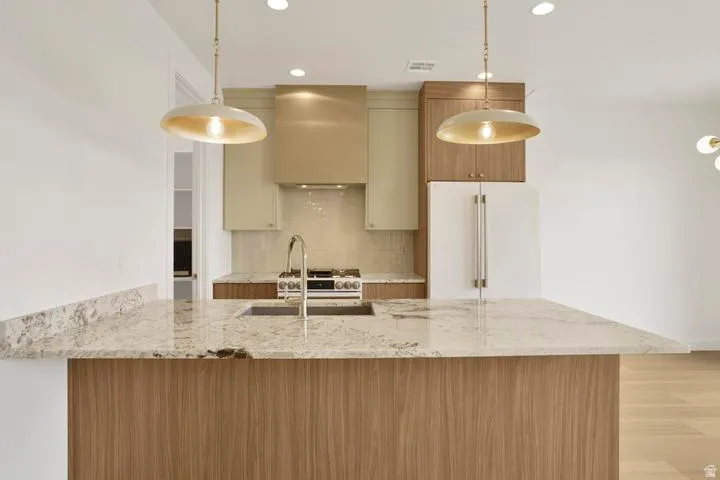 Kitchen island featuring a substantial stone countertop, integrated sink with a gooseneck faucet, and wood-finish paneling
