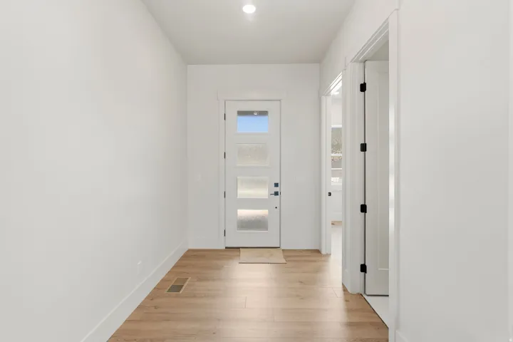 Entryway featuring a white door with frosted glass panels, wood-finish flooring, white baseboards, and a recessed ceiling light
