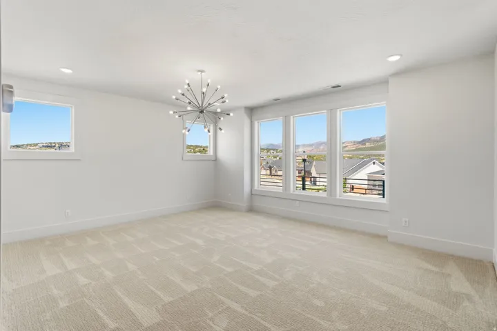 Spacious room with light-toned patterned carpeting and white walls