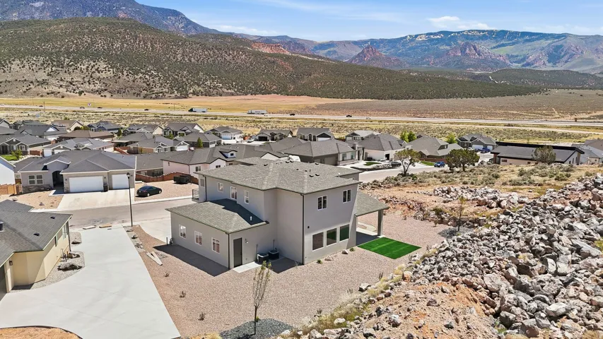 Contemporary two-story residence featuring a covered patio, artificial turf area, and a gravel landscape