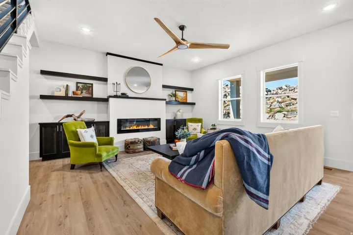 Living area featuring wood-finish flooring, a linear fireplace with a white surround, and dark built-in cabinetry with floating shelves
