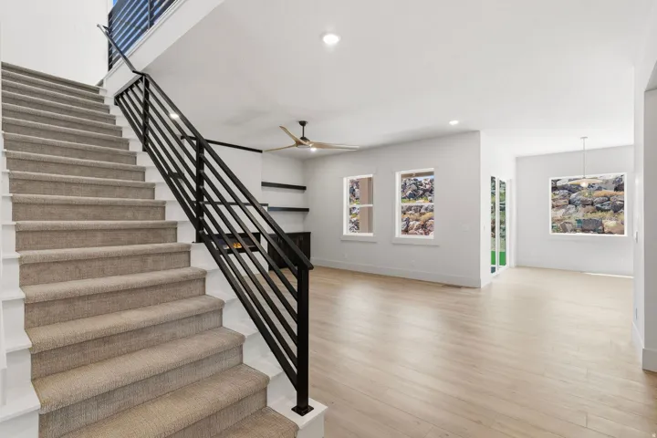 Two-story entryway featuring a carpeted staircase with contemporary black metal railings