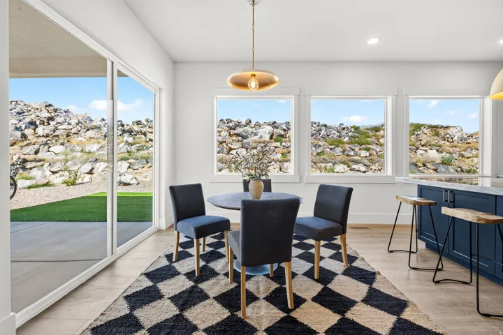 Open-concept dining area featuring light wood-finish flooring and a contemporary pendant light fixture