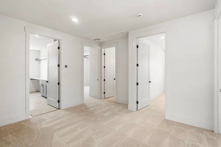 Carpeted interior area featuring recessed lighting, multiple white panel doors with matte black hardware, and light-toned walls
