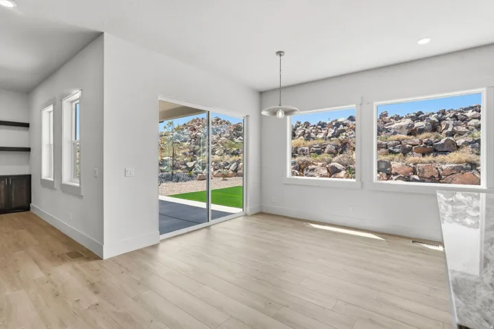 Open-concept living area featuring light wood-finish flooring, recessed lighting, and a modern pendant fixture