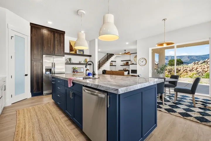 Kitchen featuring a large island with blue cabinetry and an integrated dishwasher, complemented by stone countertops and pendant lighting