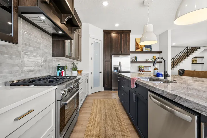 Modern kitchen featuring a professional-grade stainless steel range, light-toned countertops, and a full-height tile backsplash